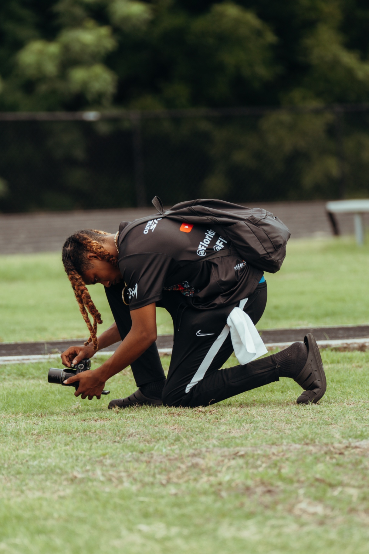 Red kneeling on the field with camera
